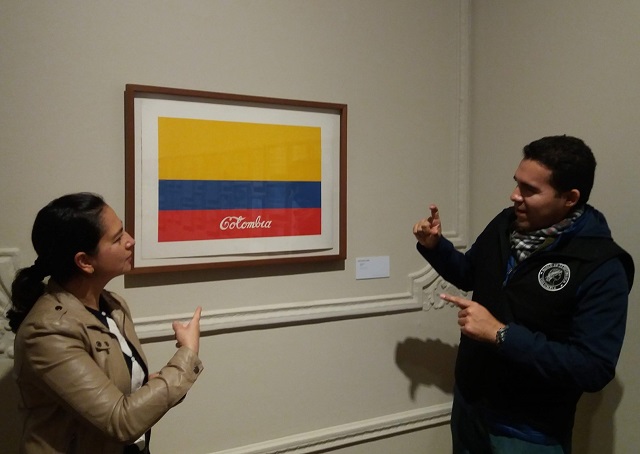 Un interprete de lengua de señas explica a una mujer la obra Colombia del artista Antonio Caro