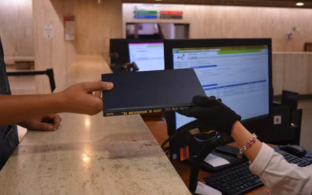 Unas manos entregando un libro a un usuario de la biblioteca