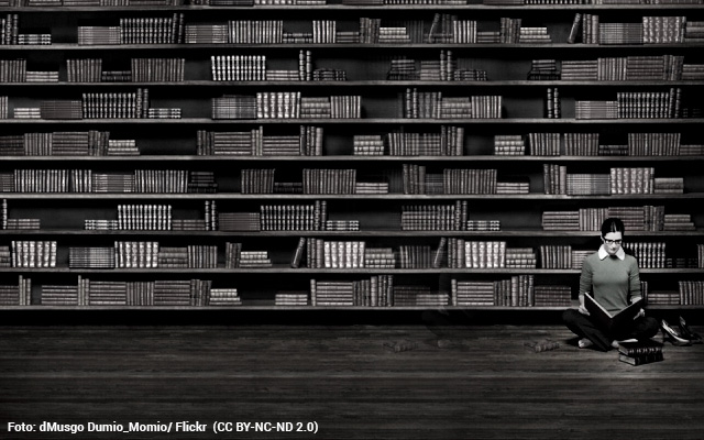 Mujer leyendo en una gran biblioteca